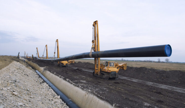 Heavy duty construction machines carrying and placing gas pipe into the ground.