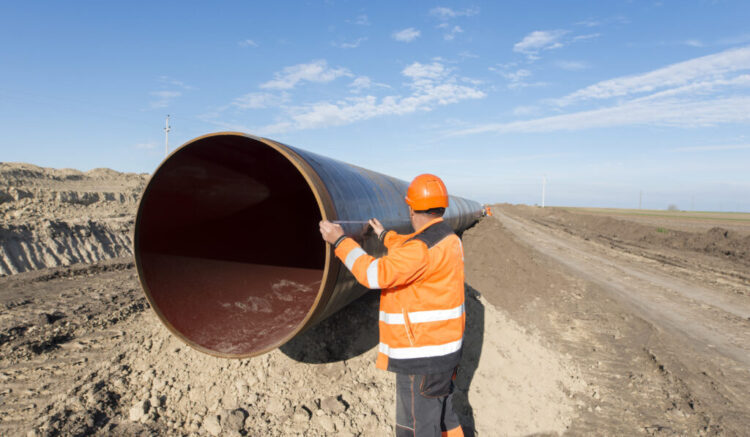 Pipeline workers measuring tube length for construction of gas and oil pipes.