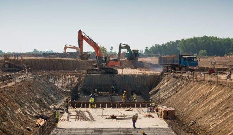 Close shot of heavy machines and construction workers working on a building